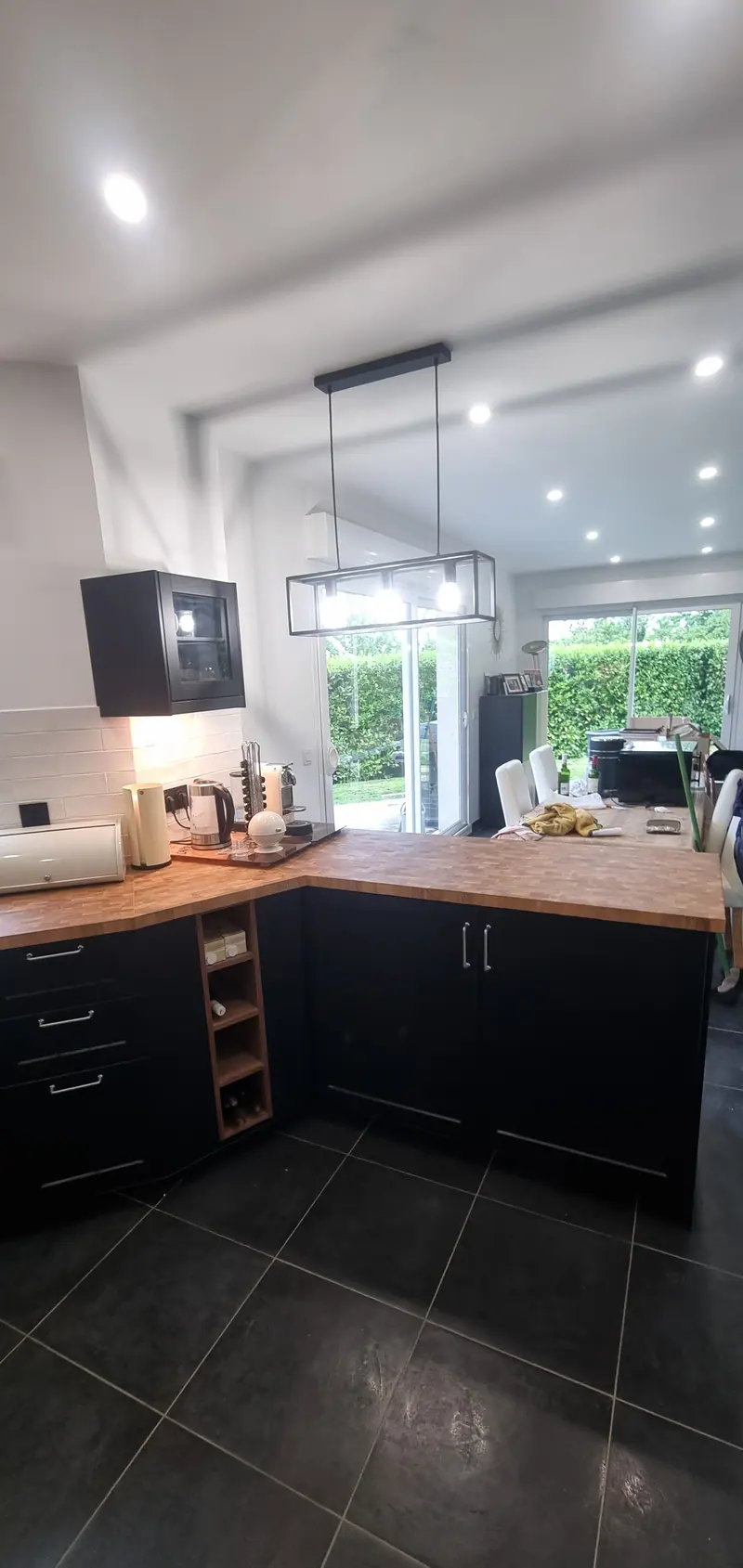 Côté salle à manger (Cuisine noire et plan de travail en bois)